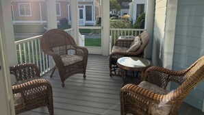 A covered porch with wicker furniture and a view of neighboring houses.