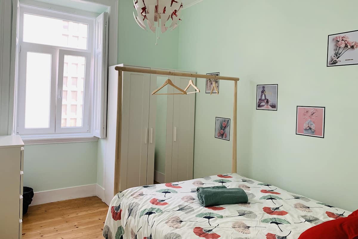 A bedroom with a bed, a wardrobe, a window, and wall art.