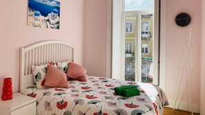 A bedroom with a bed, a nightstand, a red vase, a painting, a window, and a clock. - Memory of Lisbon (Lisbon)