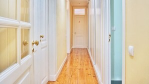 A hallway with wooden flooring, white doors, and a light switch on the wall. - Memory of Lisbon (Lisbon)