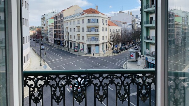 A view from a balcony overlooking a street with buildings, a clear sky, and a few parked cars. - Memory of Lisbon (Lisbon)