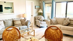 A living room with a glass coffee table, wicker chairs, and two sofas with patterned cushions. - Relaxing getaway, with picturesque views, & a short walk to St. Augustine beach. (St. Augustine)