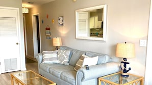 A living room with a grey sofa, two glass coffee tables, and a lamp with an anchor base. - Relaxing getaway, with picturesque views, & a short walk to St. Augustine beach. (St. Augustine)