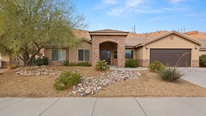 A residential house with a stone facade, a garage, and a landscaped front yard with rocks and sparse vegetation. - Exceptional 4 Bedroom Vacation Home near Palmer Golf Course (Mesquite)