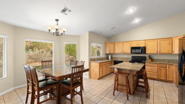 A spacious kitchen with wooden cabinets, a granite countertop, and a dining area with a table and chairs. - Exceptional 4 Bedroom Vacation Home near Palmer Golf Course (Mesquite)