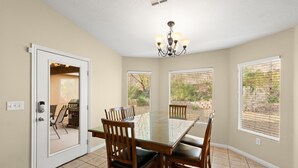 A dining area with a glass-top table, wooden chairs, and a chandelier. - Exceptional 4 Bedroom Vacation Home near Palmer Golf Course (Mesquite)