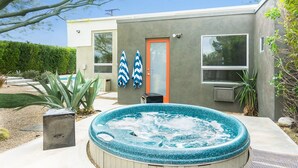 Una casa moderna con un jacuzzi, una puerta y dos sombrillas.