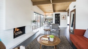 Una sala de estar moderna con chimenea, una mesa de centro redonda y un sofá rojo.