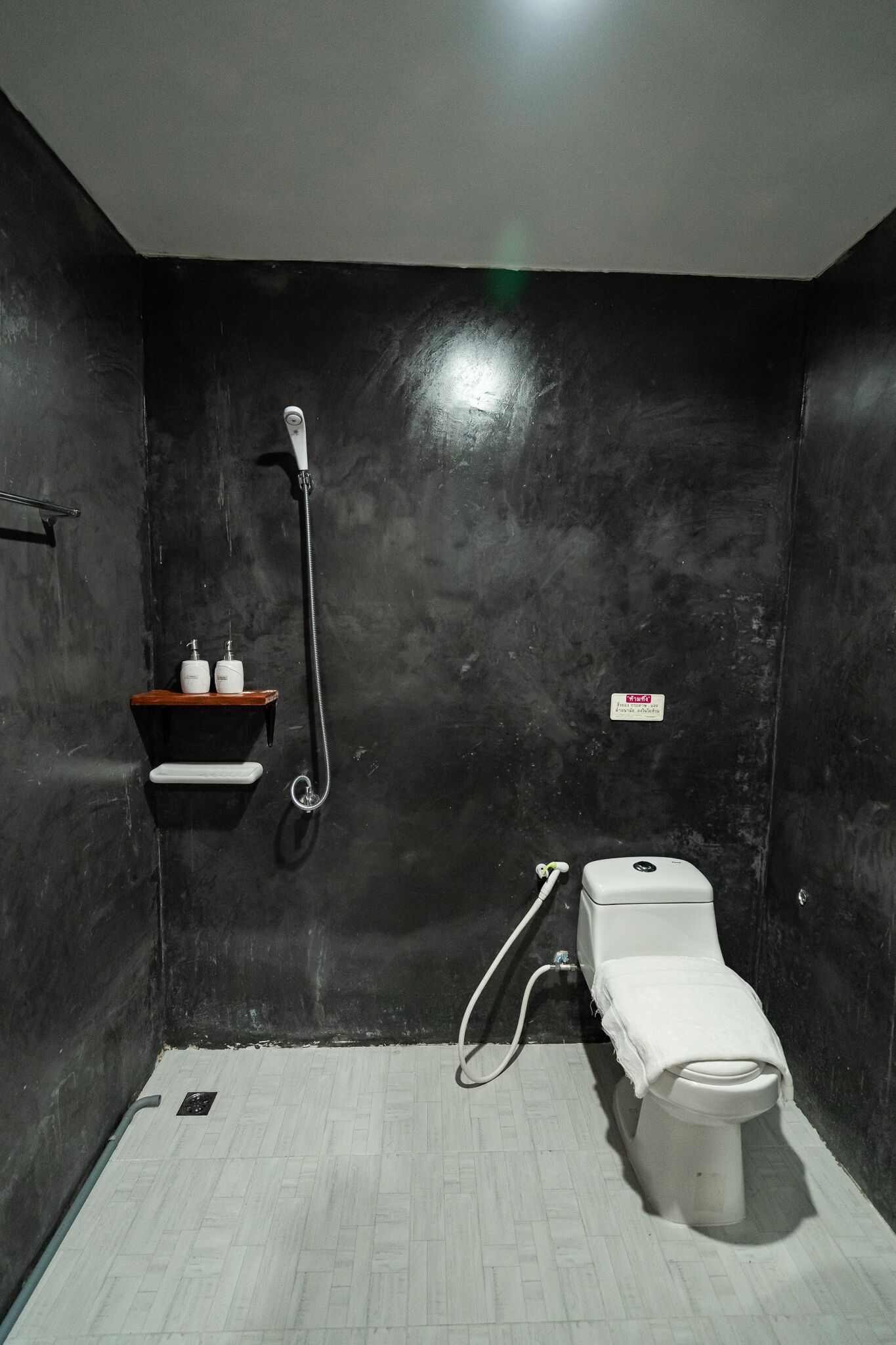 Un baño pequeño con inodoro, ducha y un estante con artículos de aseo.