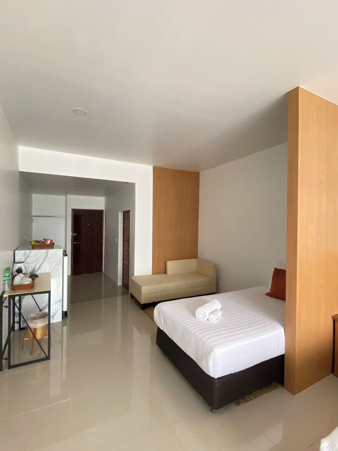 Quarto de hotel moderno com cama, pequena escrivaninha, uma cadeira e um sofá.