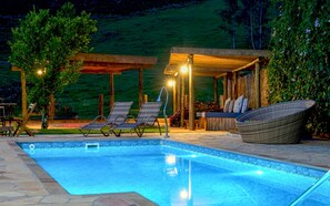A swimming pool with lounge chairs and a covered seating area, surrounded by greenery. - Chalés Santa Catarina (Socorro)