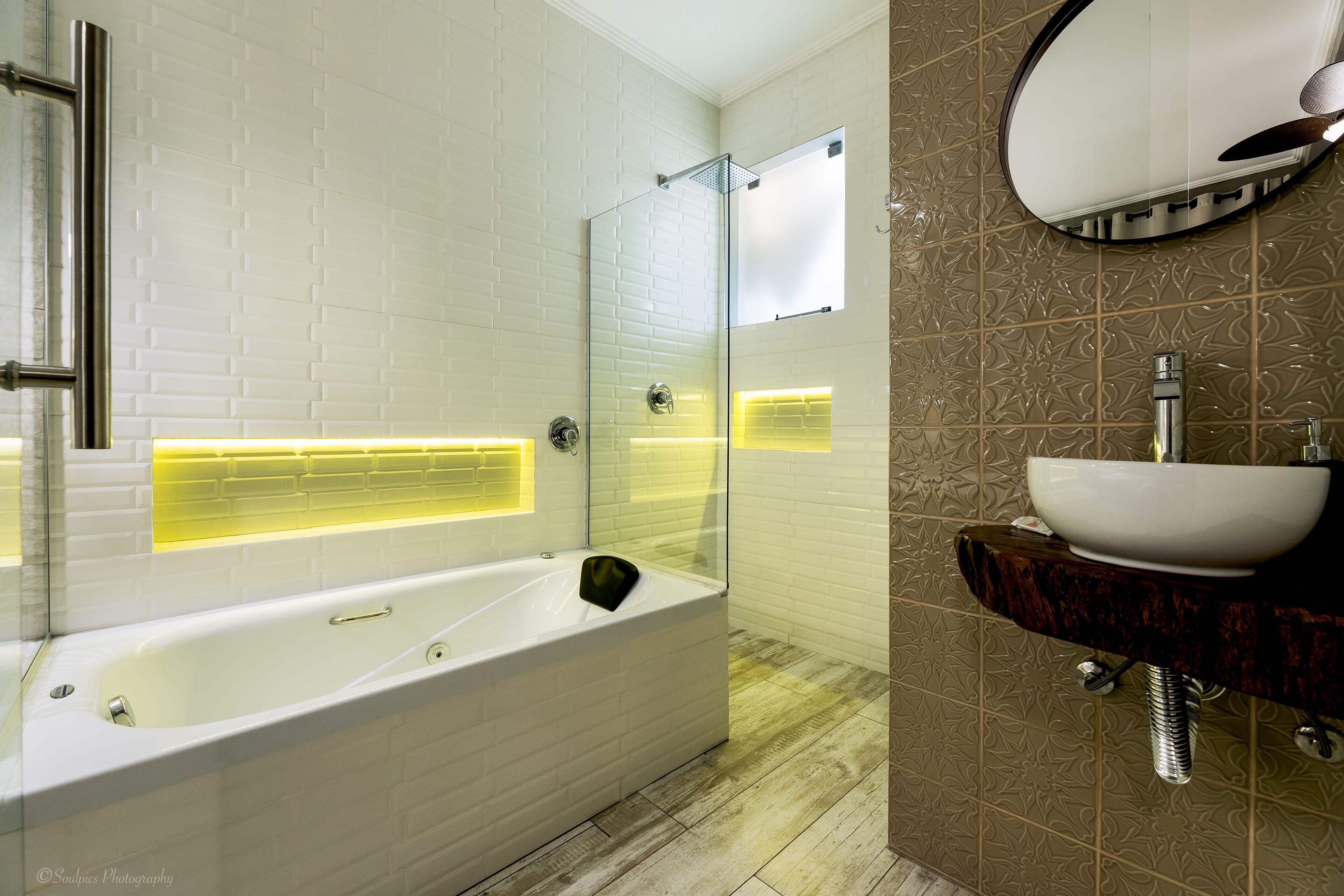 A modern bathroom with a white bathtub, a glass shower enclosure, and a vanity with a white sink.