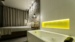 A modern bathroom with a large bathtub, a mirror with a yellow light strip, and a stone wall. - Chalés Santa Catarina (Socorro)