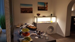 Un buffet de petit-déjeuner proposant une variété d’aliments, une machine à café et des œuvres d’art décoratives murales.