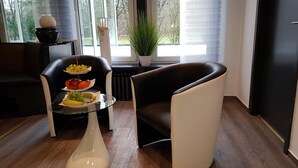 Un salon moderne avec une table basse en verre, un présentoir à fruits à trois niveaux et un fauteuil en cuir.