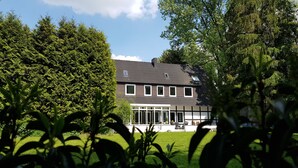 Une maison à deux étages, avec un toit sombre, des boiseries blanches et de nombreuses fenêtres.