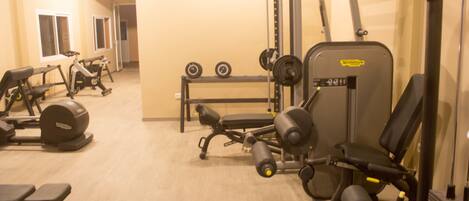 A gym with various exercise equipment including treadmills, weight machines, and dumbbells.