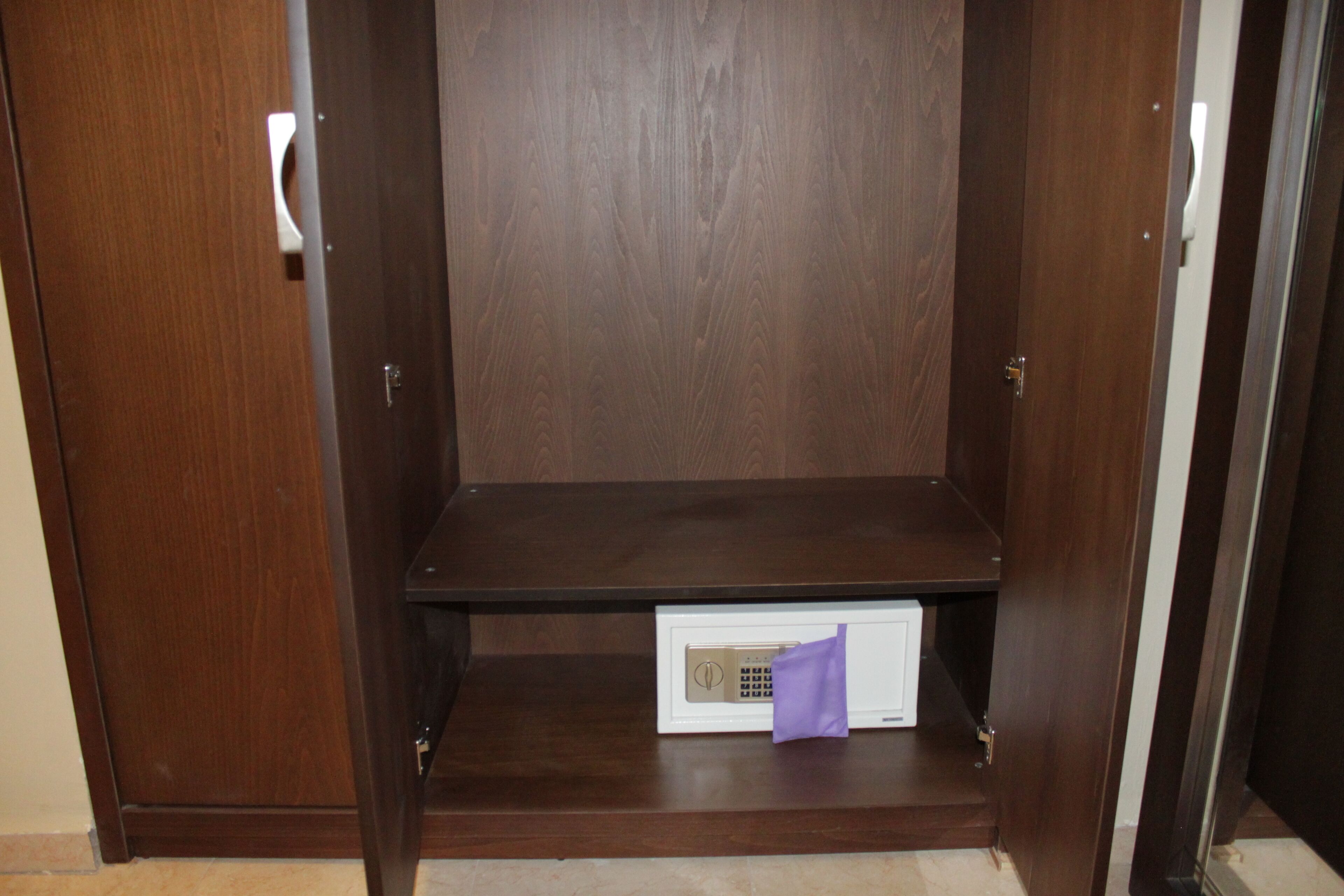 Une armoire en bois avec une étagère intégrée et un appareil électronique blanc posé sur l’étagère inférieure.