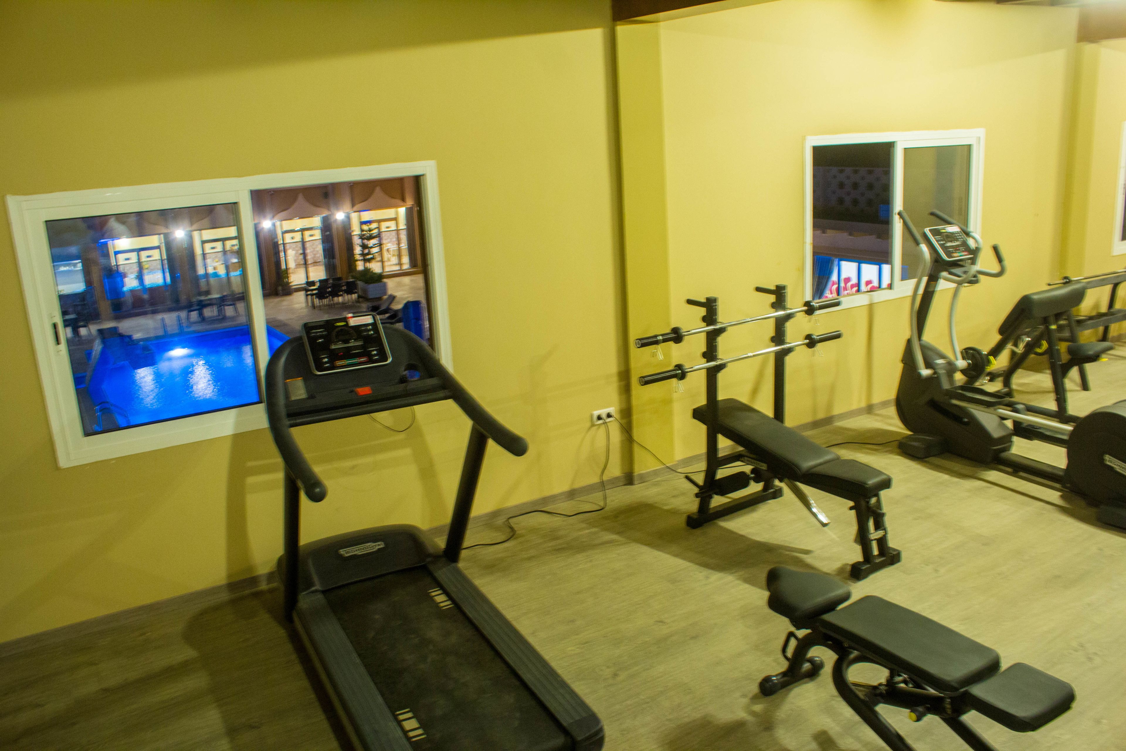 A gym with a treadmill, bench press, and weight machines.