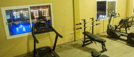 A gym with a treadmill, bench press, and weight machines.