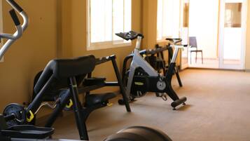 Varias bicicletas estáticas en un gimnasio con ventanas amplias y vistas al exterior.