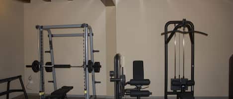 A gym with weightlifting equipment, benches, and a squat rack.