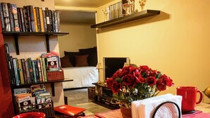 A dining area with red plates, a table set with red cups, a vase with red roses, and a bookshelf filled with books. - Two Rivers Relaxing Retreat  (Portland)