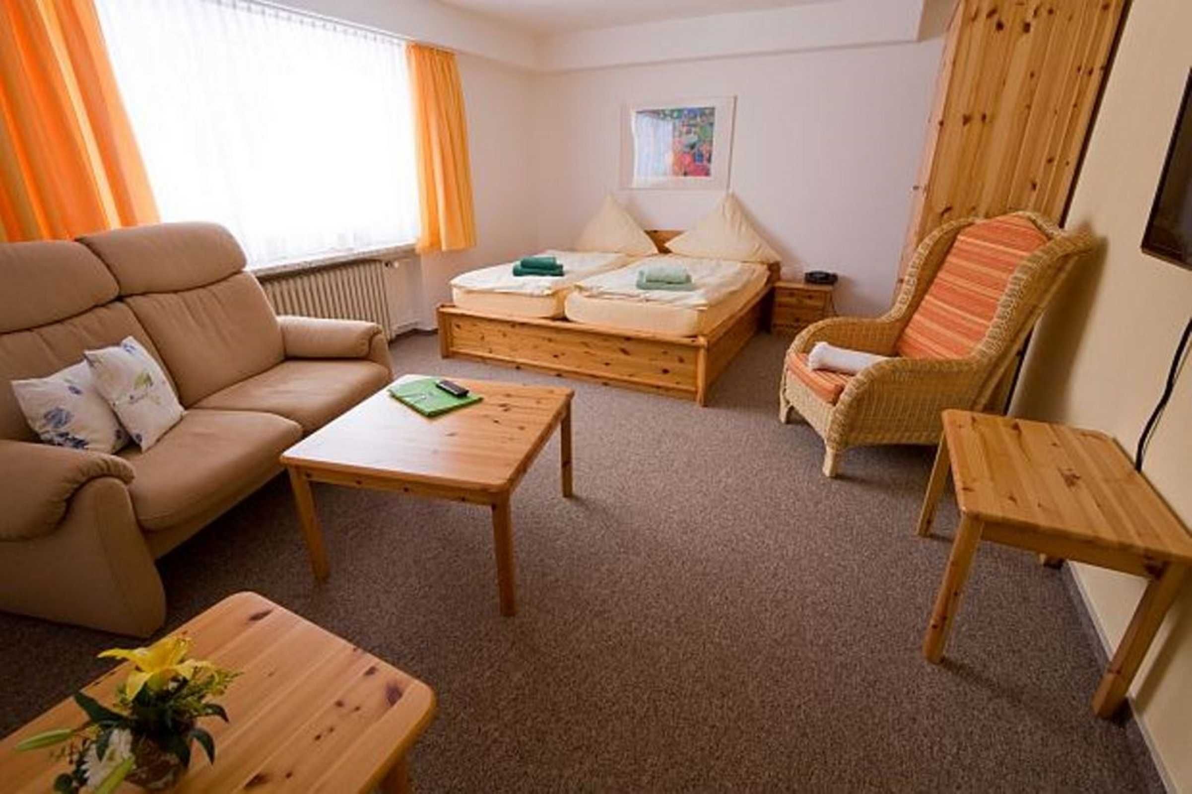 Una habitación con sofá, cama, mesa de madera y una silla.