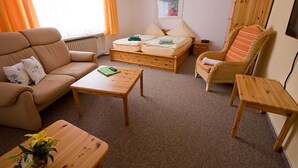 A room with a sofa, a bed, a wooden table, and a chair. - Apartment 1 - Panorama house (Sankt Andreasberg)