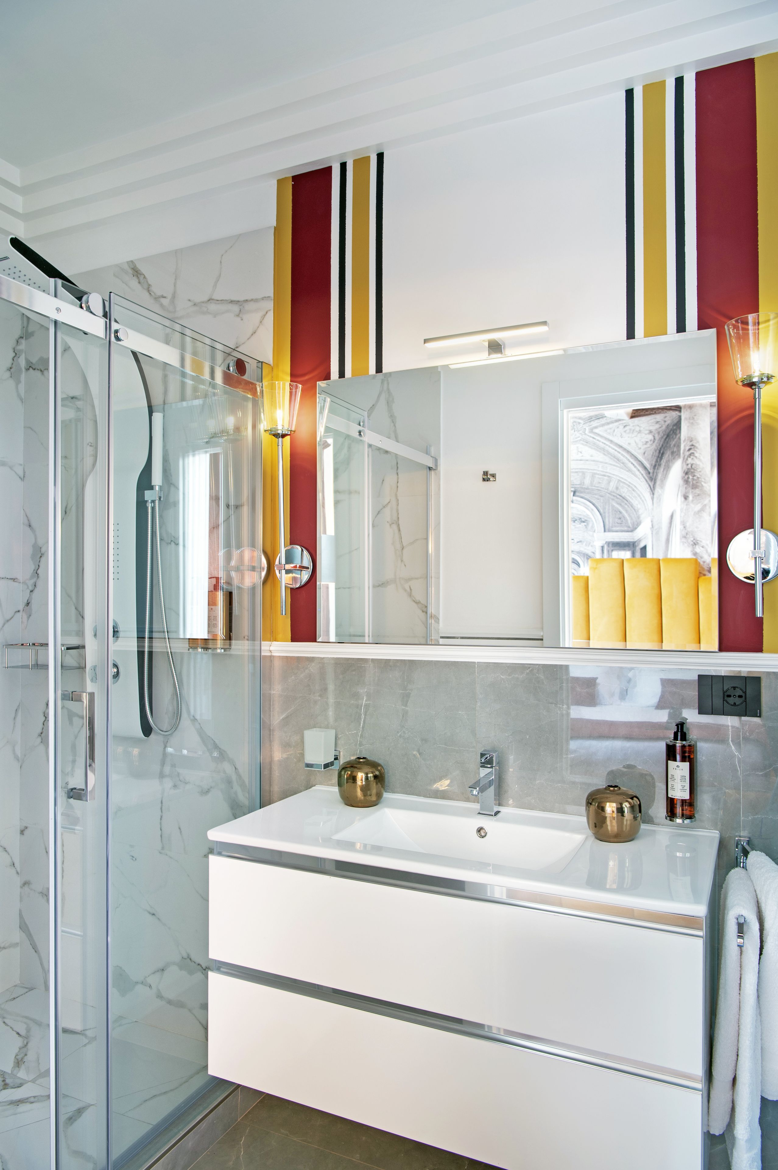 Een moderne badkamer met een douchecabine van glas, een wit badkamermeubel met twee wasbakken en een grote spiegel.
