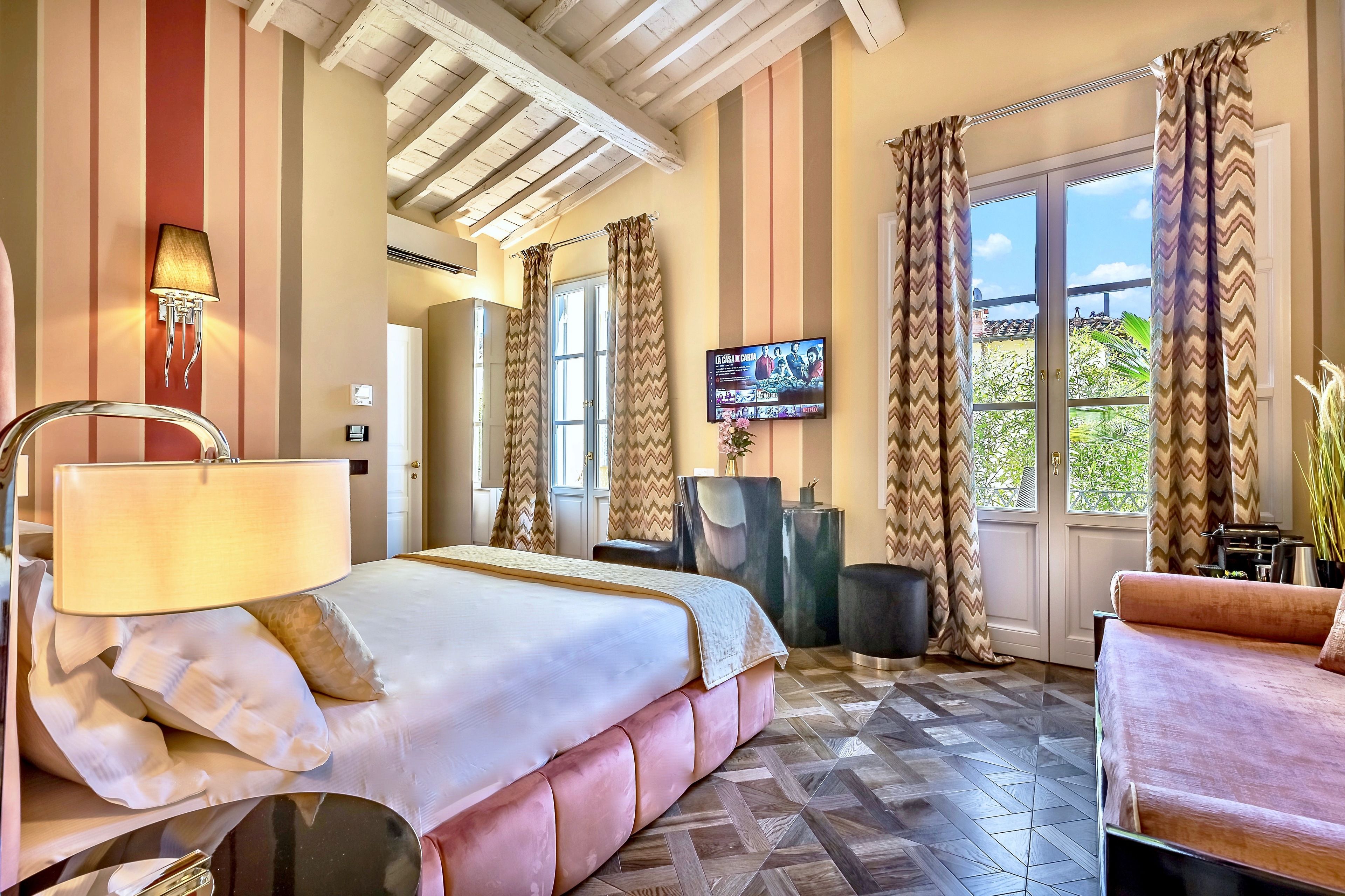 Habitación de hotel con una cama grande, un escritorio, un televisor y vistas al exterior.