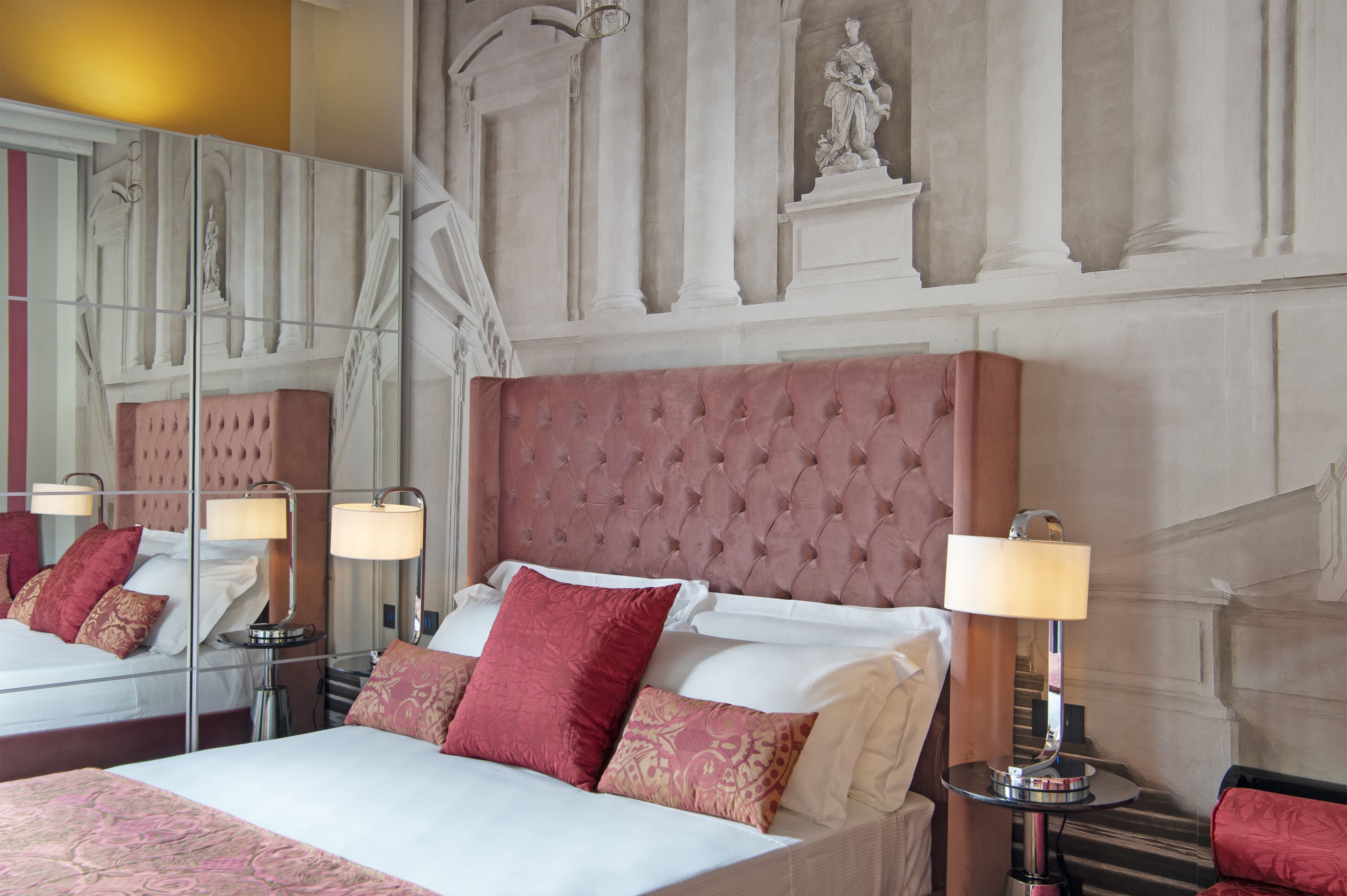 Ein Hotelzimmer mit einem großen Bett, einem Spiegel und einer Statue an der Wand.