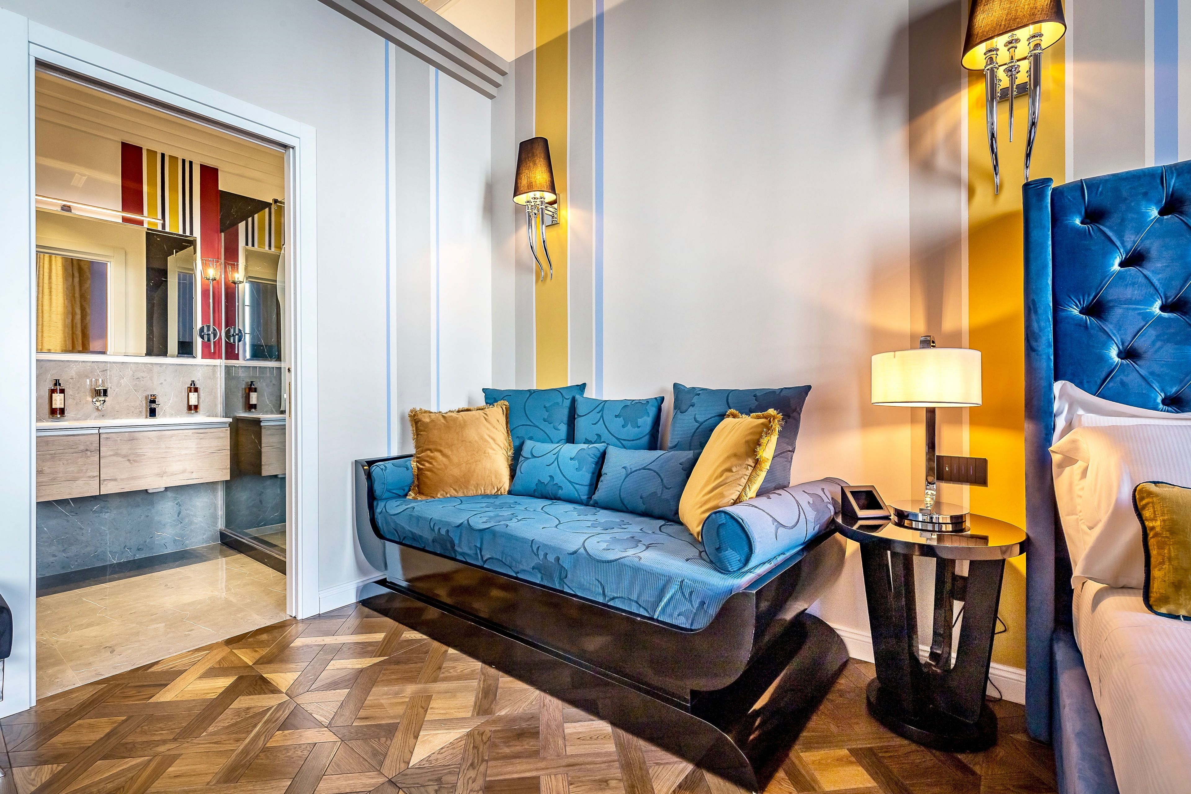 Una habitación de hotel moderna con sofá, cama, mesita de noche y espejo.