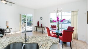 A dining area with a granite countertop, red chairs, and a chandelier.