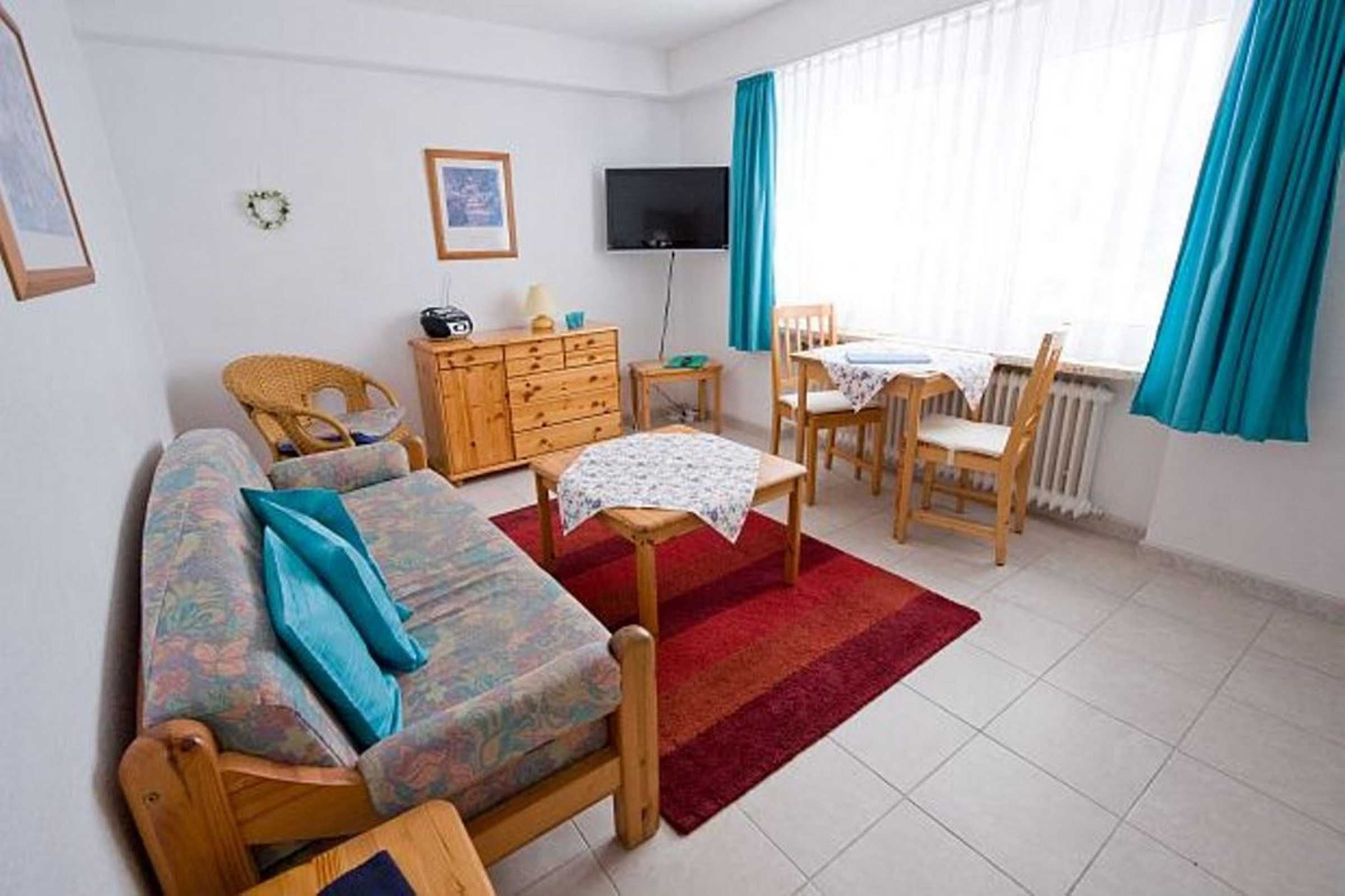 Una habitación amoblada con sofá, una mesa pequeña, televisor, cómoda y comedor.