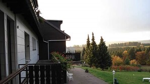Ein Gebäude mit Balkon, einem gepflasterten Weg und einer Grünfläche mit Bäumen.