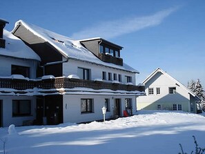 A two-story building with a snow-covered roof and a balcony. - Apartment 4 - Panorama of the house (Sankt Andreasberg)