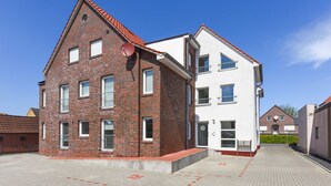 A two-story building with a brick facade and a white upper section, featuring a balcony and a satellite dish. - Apartment Hanseatic city Zwolle (Wittmund)