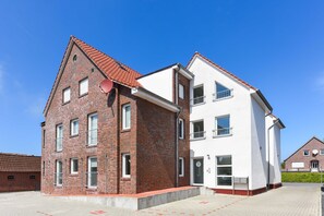 Un bâtiment à deux étages, avec une façade en briques rouges et une partie supérieure blanche.