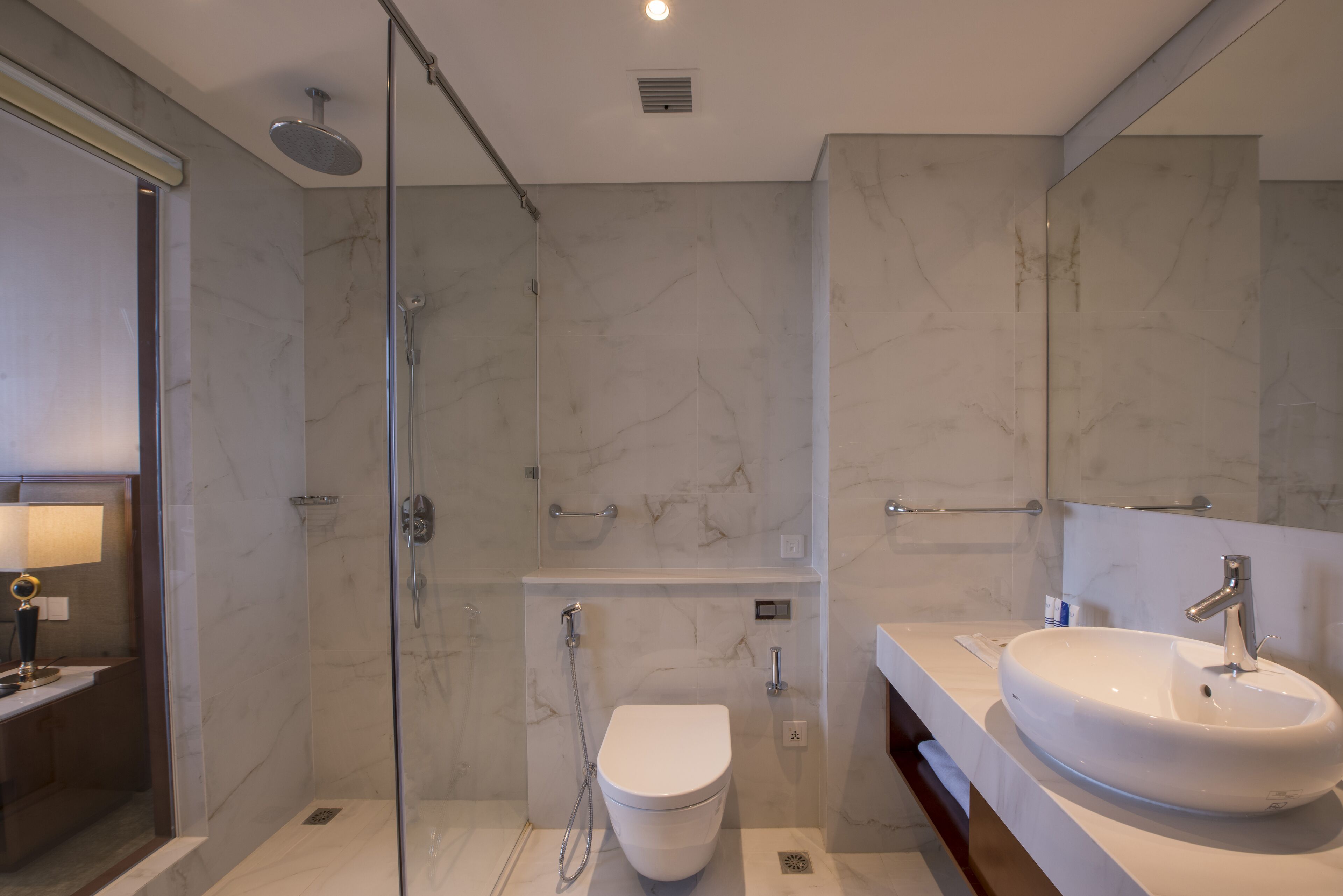Ein modernes Badezimmer mit einer Duschkabine, einer weißen Toilette und einem großzügigen Waschbecken mit Spiegel darüber.