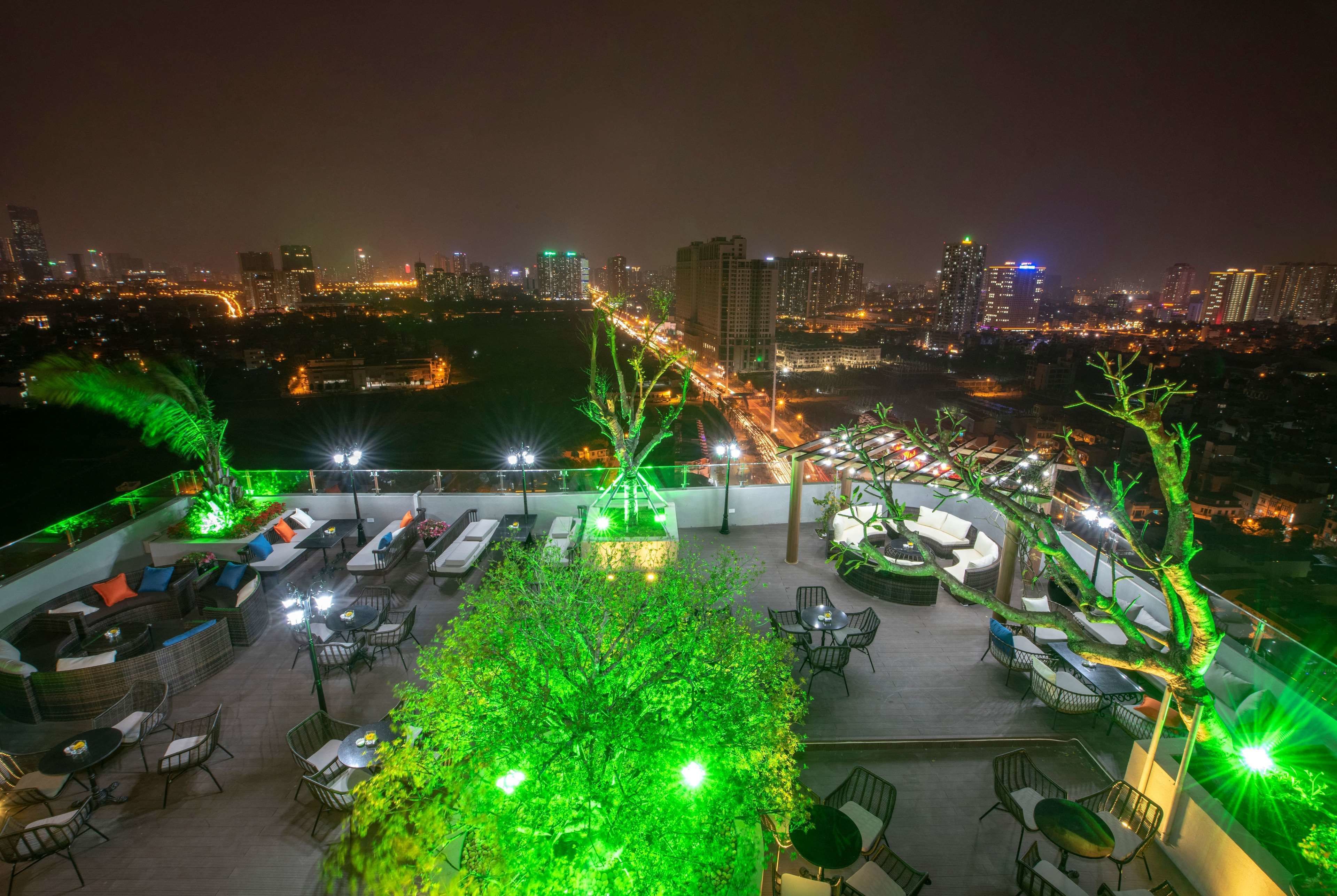 A rooftop terrace with outdoor seating and a view of the city skyline at night.