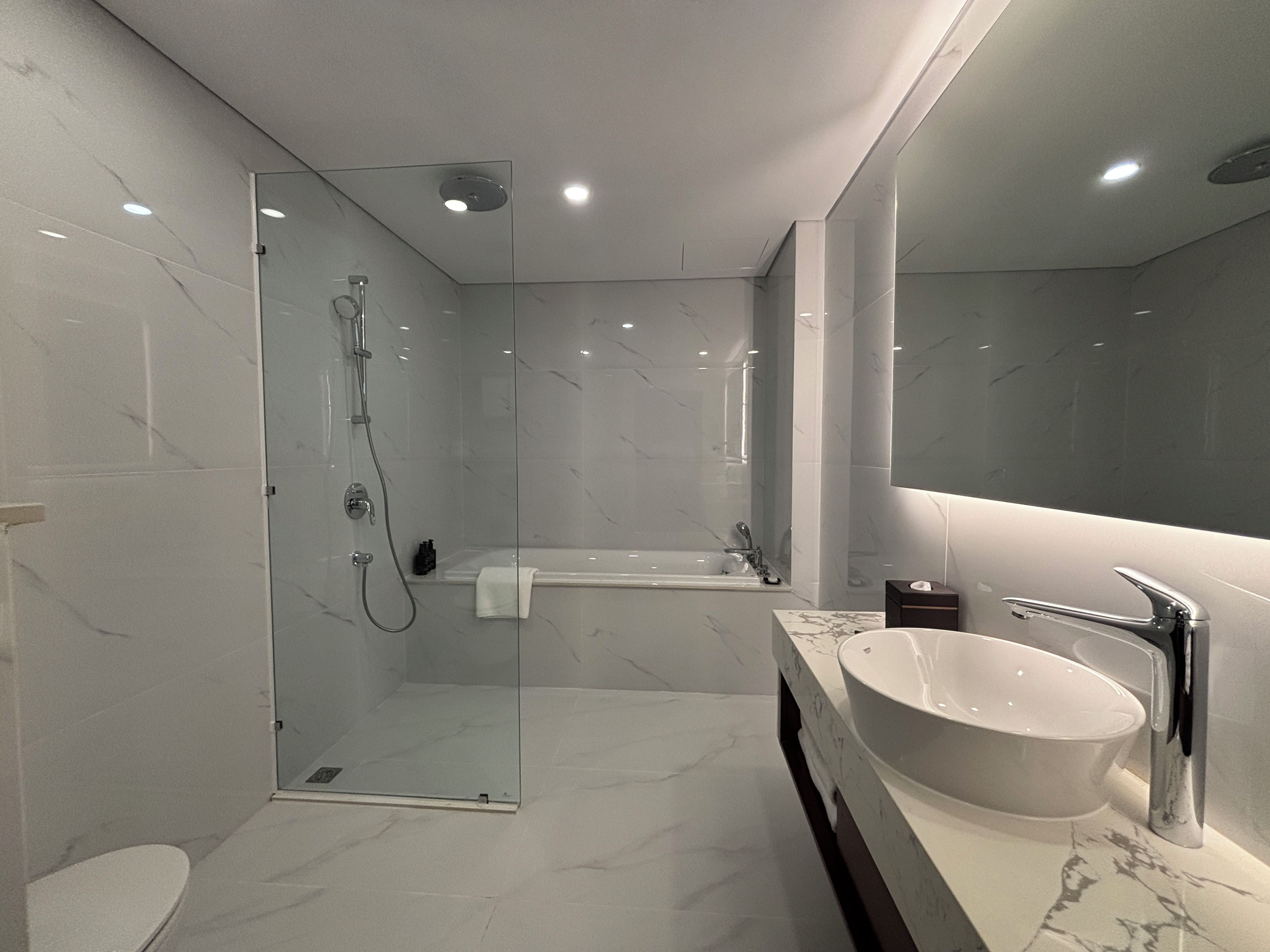A modern bathroom with a glass-enclosed shower, a freestanding bathtub, and a large vanity with a basin.