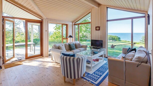 Amplia sala de estar con un televisor grande, asientos cómodos y vista al mar.