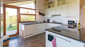 Una cocina moderna con armarios blancos, un ventanal y vistas al exterior.