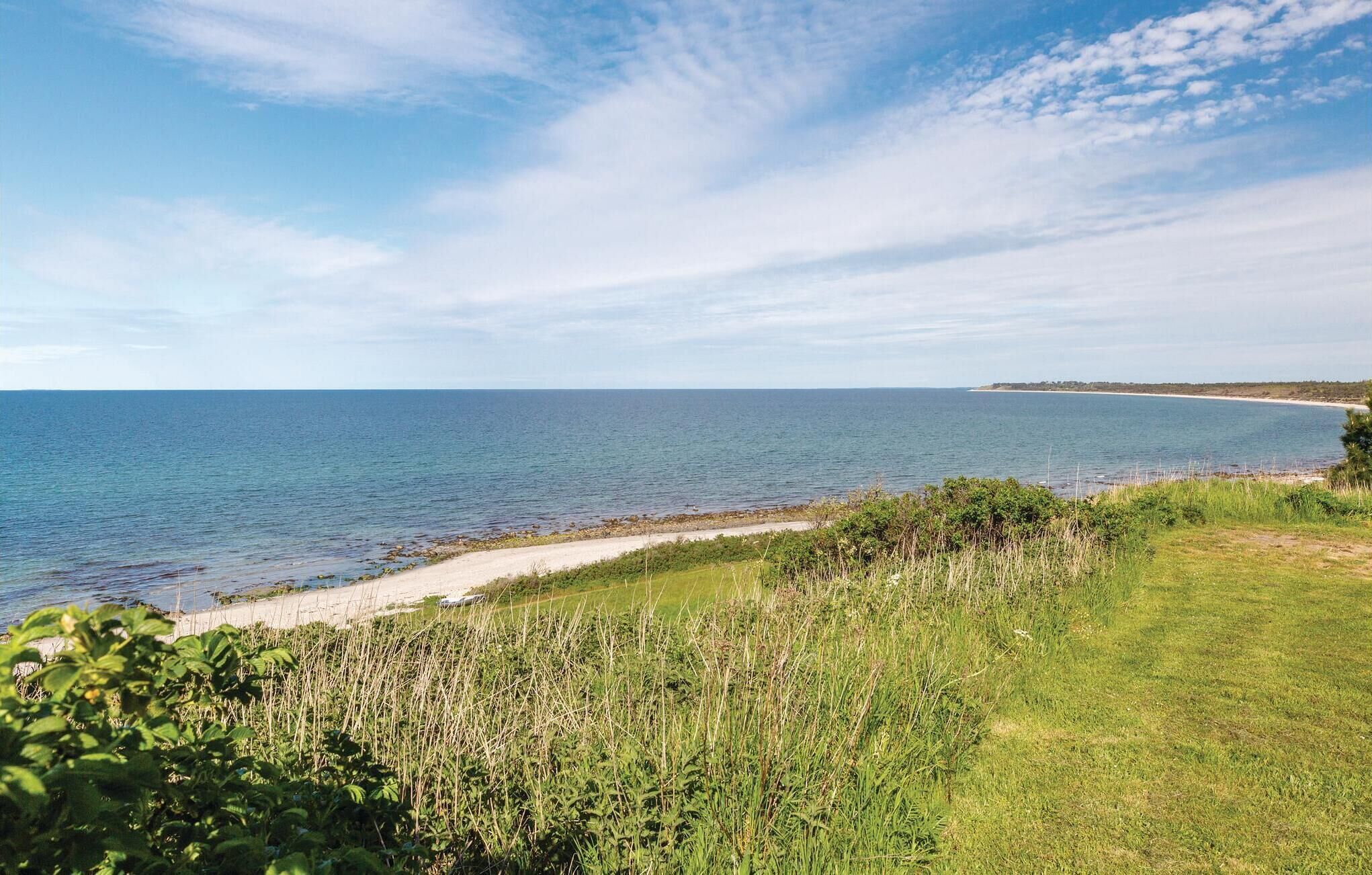 Et kystlandskab med en sandstrand, grønne områder og kig til havet.