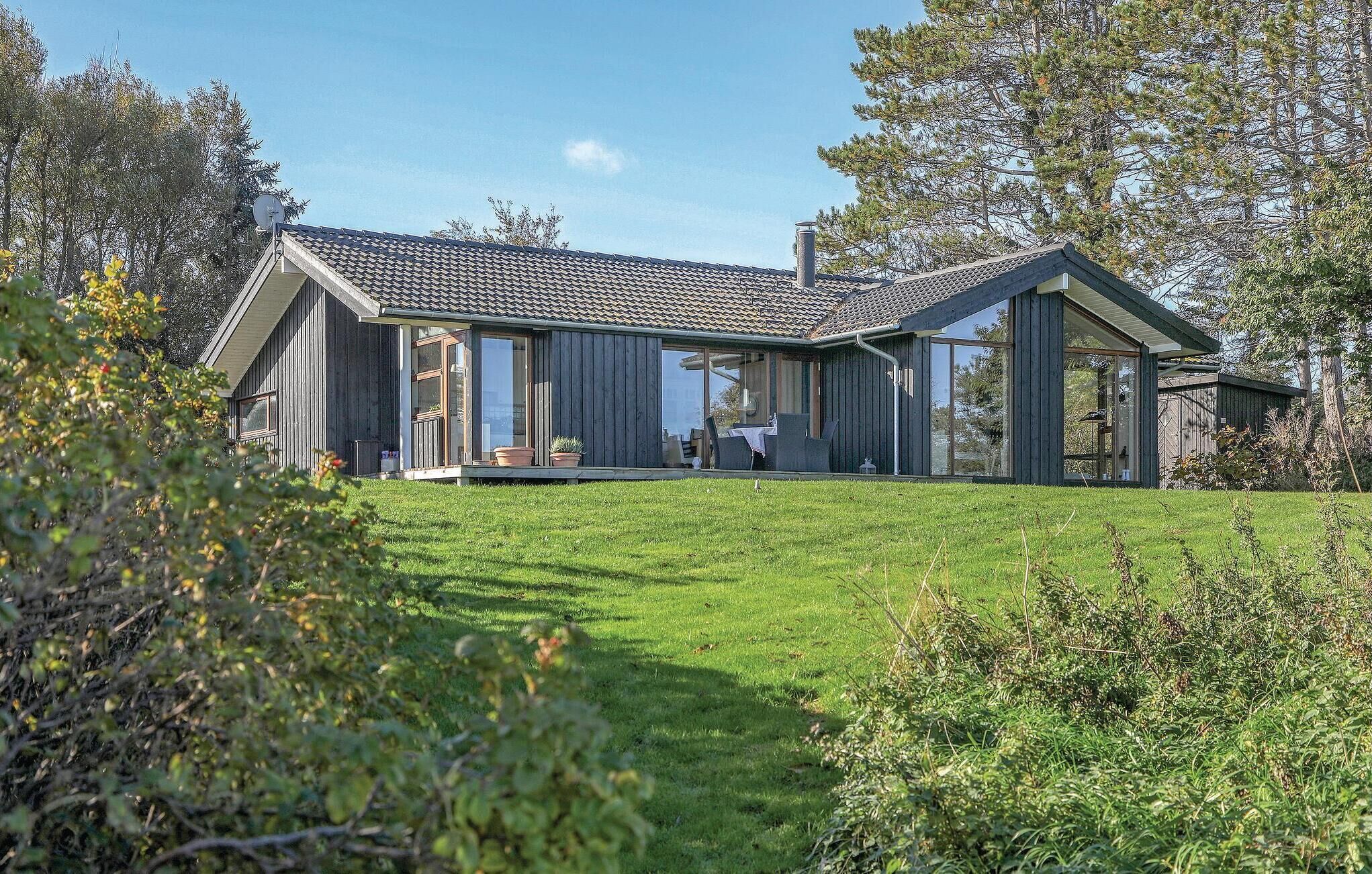 Et moderne hus med stor glasfacade og en rummelig patio.
