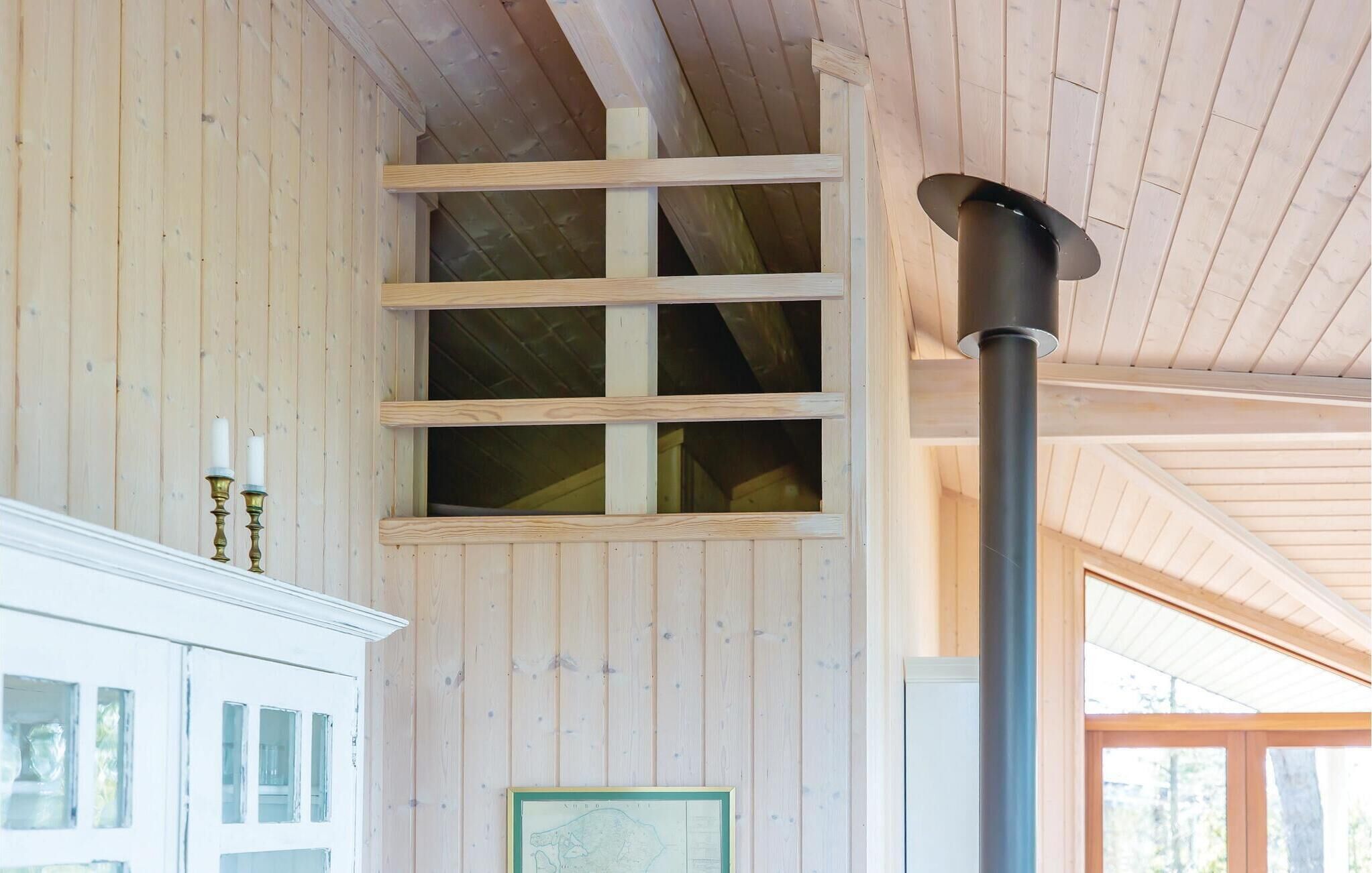 A wooden interior with a loft area, a fireplace, and a framed map on the wall.