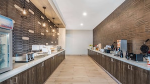 A modern kitchen with wooden cabinets, a central island, and various appliances. - La Quinta Inn and Suites by Wyndham Houston Spring South (Spring)