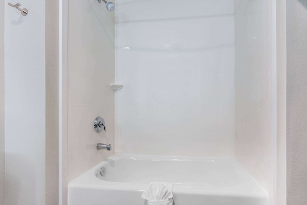 Un baño blanco con bañera, ducha e inodoro.