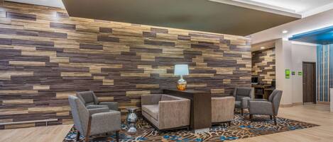 Un vestíbulo de diseño moderno con un panel de pared de madera, un mostrador de recepción y una zona de estar con alfombra estampada.